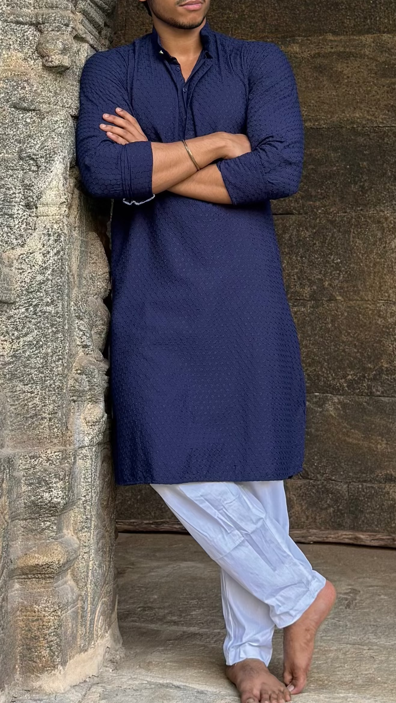 Man in a blue kurta standing in front of stone architecture